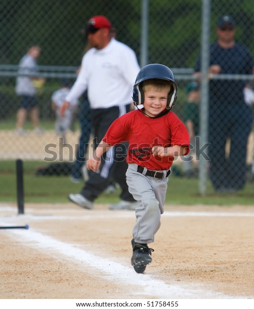 Young\
baseball player running and smiling during\
game