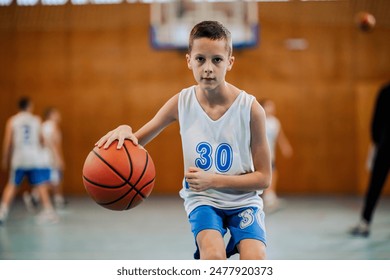 A young basketball player with an intense stare holds the ball, ready to make a play in a sport competition - Powered by Shutterstock