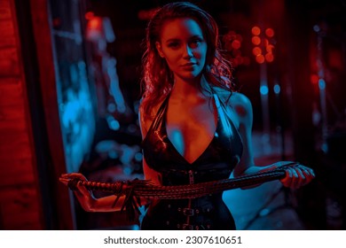 Young bdsm style woman with whip portrait in black latex suit