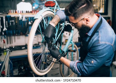 Young beard bicycle mechanic repairing bicycles in a workshop.	 - Powered by Shutterstock