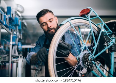 Young beard bicycle mechanic repairing bicycles in a workshop.	