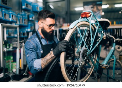 Young beard bicycle mechanic repairing bicycles in a workshop.	 - Powered by Shutterstock