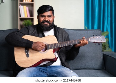 Young Beard Man Teaching About Guitar By Looking At Camera From Home - Concept Of Online Or Virtual Music Class, Hobbies And Professional Artist.