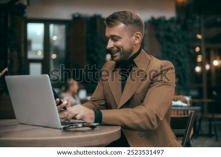 Young beard man using laptop on office, freelance work, outdoor close up hipster portrait, brutal, guy listening music on earphones, make photo and video, production, Bali, coffee cup, smartphone