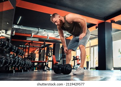 A young bearded athletic man trains with dumbbells in the gym. Bottom view. The concept of fitness and healthy lifestyle. - Shutterstock ID 2119429577