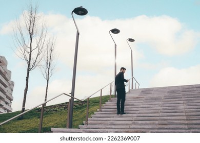 Young bearded elegant businessman outdoors using smartphone and tablet walking upstairs - Powered by Shutterstock