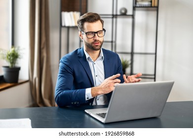 Young Bearded Entrepreneur, Business Coach In Formal Wear Having Coaching Session On Leadership And Sales Or Discussing Project, Gesturing, Presenting Strategy, Idea Online On Video Call Via Laptop