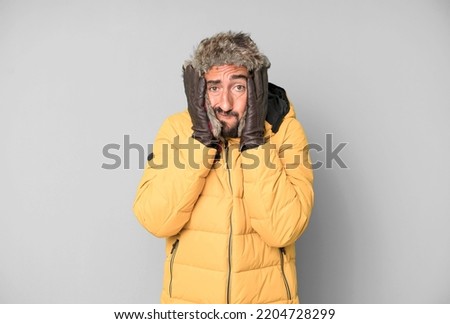 young bearded and expressive man cold and winter concept and wearing an anorak.