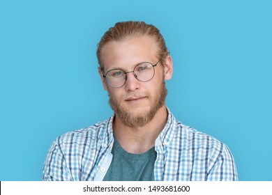 Young Bearded Handsome Man Blond Hair Hipster Face Wearing Optical Glasses Looking At Camera, Millennial Handsome Casual Guy Isolated On Blue Studio Blank Background, Close Up View Headshot Portrait