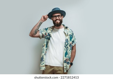Young bearded hipster wearing Hawaiian shirt, hat and white blank t-shirt with copy space for text or logo. Layout for design