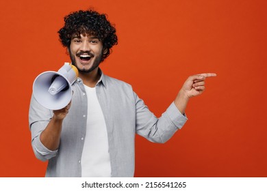Young bearded Indian man 20s wears blue shirt hold scream in megaphone announces discounts sale Hurry up point on workspace area copy space mock up isolated on plain orange background studio portrait - Shutterstock ID 2156541265