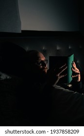 Young Bearded Male Reading Book In Bed. Low Light. Night Life. Relaxing.