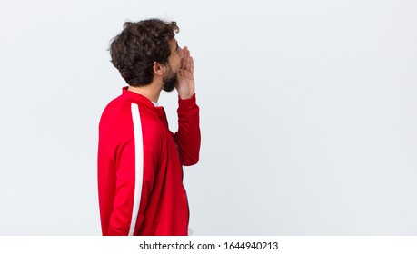 Young Bearded Man Back View Profile View, Looking Happy And Excited, Shouting And Calling To Copy Space On The Side Against Copy Space Wall