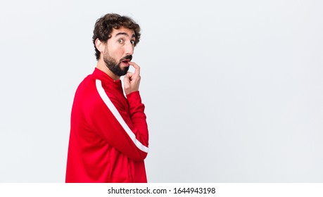 Young Bearded Man Back View With Surprised, Nervous, Worried Or Frightened Look, Looking To The Side Towards Copy Space Against Copy Space Wall