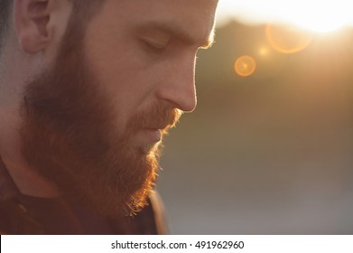 young bearded man with closed eyes on the background of the sun's rays