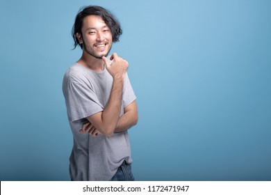 Young bearded man confident finger touching chin portrait in blue background. Asian young hipster standing finger touching jaws, confident smile, half body shot. Young generation hipster concept. - Powered by Shutterstock