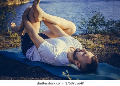 Young Bearded Man Doing Yoga Headstand And Standing Asana. Beautiful Mountain Quarry Lake Landscape Background. Complex Amazing And Funny Yoga Picture. International Day Of Yoga