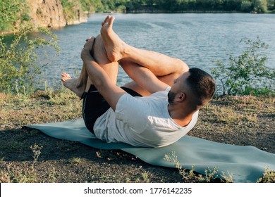 Young Bearded Man Doing Yoga Headstand And Standing Asana. Beautiful Mountain Quarry Lake Landscape Background. Complex Amazing And Funny Yoga Picture. International Day Of Yoga