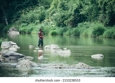 Young Bearded Man Fishing At A Lake Or River. Flyfishing.