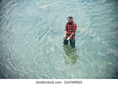 Young Bearded Man Fishing At A Lake Or River. Flyfishing.