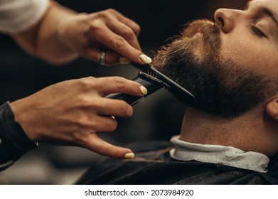 Young bearded man getting beard haircut by hairdresser at barbershop - Powered by Shutterstock