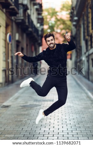 Young bearded man jumping in urban street