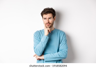 Young bearded man looking pensive and frowning, thinking about problem or trouble, standing worried against white background