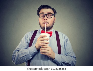 Young Bearded Man With Overweight Holding Eyes Closed And Drinking Sweet Soda With Deep Enjoyment