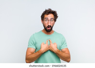 young bearded man pointing to self with a confused and quizzical look, shocked and surprised to be chosen