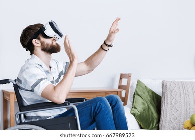 Young bearded man sitting on wheelchair playing in VR - Powered by Shutterstock