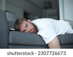 Young bearded man sleep at home on couch with his cell mobile phone in living room. Smartphone addiction concept. 