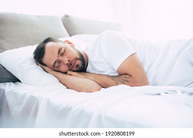 Young bearded man is sleeping on the bed