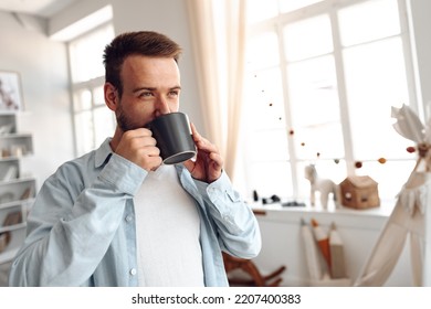 Young bearded man smiling and drinking coffee at home - Powered by Shutterstock