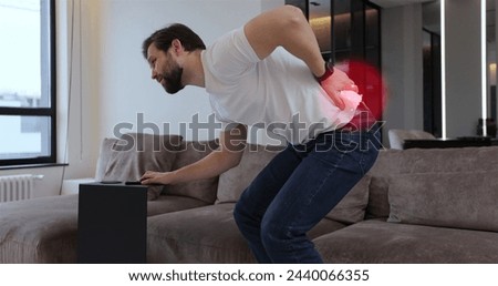 Young bearded man with spinal problems bends over with back pain at home, digital 3d animation with red pulsating sore zone of problem area.