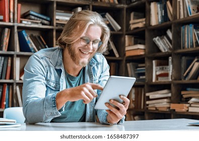 Der junge Bärenmann Schüler-Hipster-Lehrer Brille Büro-Bibliothek Schreibtisch moderne Tablet-Computer verwenden App Surf Netz Social Network ansehen Video-Anruf Hahn Touchscreen-Kopienraum.