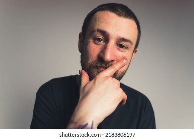 Young Bearded Man With Tattoo On His Face Touches His Face, Tattooed Arm Isolated Copy Space Studio Shot Medium Closeup . High Quality Photo