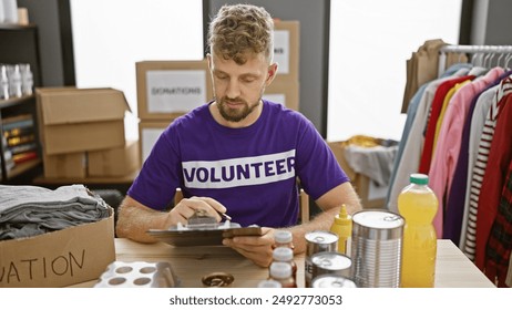 Young bearded man in volunteer shirt sorting donations in a well-organized warehouse. - Powered by Shutterstock