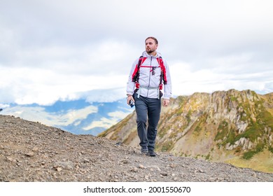 Young Bearded Man Wearing White Puff Jacket Standing Near A Mountain