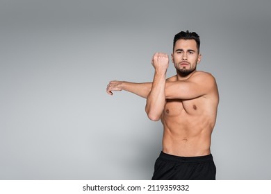 young bearded and muscular sportsman warming up on grey - Powered by Shutterstock