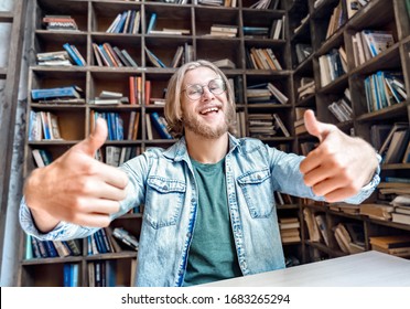 Young bearded smiling student man teen hipster blogger vlogger glasses look at camera hold thumbs up cool gesture shoot vlog youtube channel home library encourage followers stream online. - Powered by Shutterstock