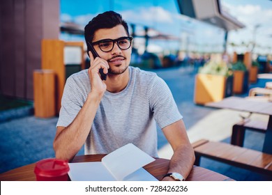 Young bearded student in eyeglasses talking on phone with best friend about common homework project while sitting in cafe, pensieve hipster guy contact banking service feeling bored listening operator - Shutterstock ID 728426236