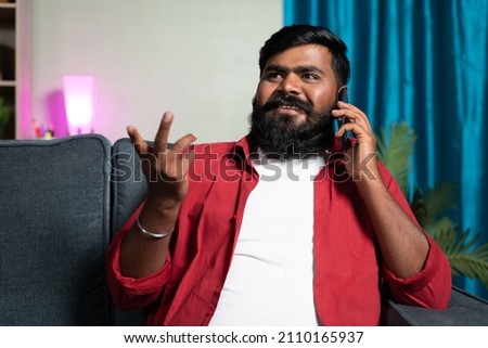 young beardman talking or speaking on mobile phone at home - concept of communication skill and leisure activities. Stock photo © 