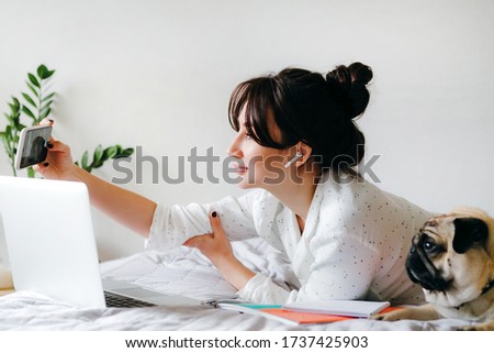Young beatiful girl is taking selfie while studying and working at home. Home office. Concept of working in isolation.