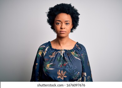 Young beautiful African American afro woman with curly hair wearing casual floral dress with serious expression on face. Simple and natural looking at the camera. - Powered by Shutterstock