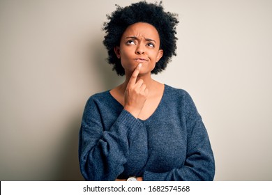 Young beautiful African American afro woman with curly hair wearing casual sweater Thinking concentrated about doubt with finger on chin and looking up wondering