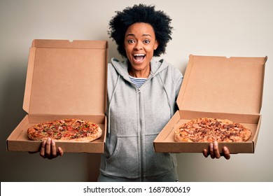 Young Beautiful African American Afro Woman Smiling Happy And Confiden. Standing With Smile On Face Holding Carton Boxes With Italian Fresh Pizza Over Isolated White Background