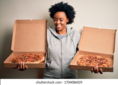 Young Beautiful African American Afro Woman Smiling Happy And Confiden. Standing With Smile On Face Holding Carton Boxes With Italian Fresh Pizza Over Isolated White Background