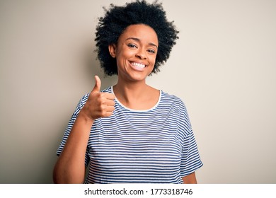 Young beautiful African American afro woman with curly hair wearing striped t-shirt doing happy thumbs up gesture with hand. Approving expression looking at the camera showing success.