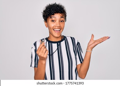 Young beautiful african american afro referee woman wearing striped uniform using whistle very happy and excited, winner expression celebrating victory screaming with big smile and raised hands - Powered by Shutterstock