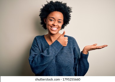 Young beautiful African American afro woman with curly hair wearing casual sweater Showing palm hand and doing ok gesture with thumbs up, smiling happy and cheerful